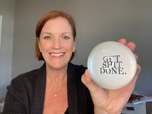 Melanie Cameron holding a paperweight that says Get Shit Done