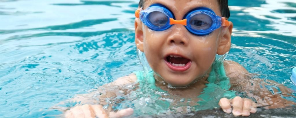 Child wearing blue goggles in swimming pool