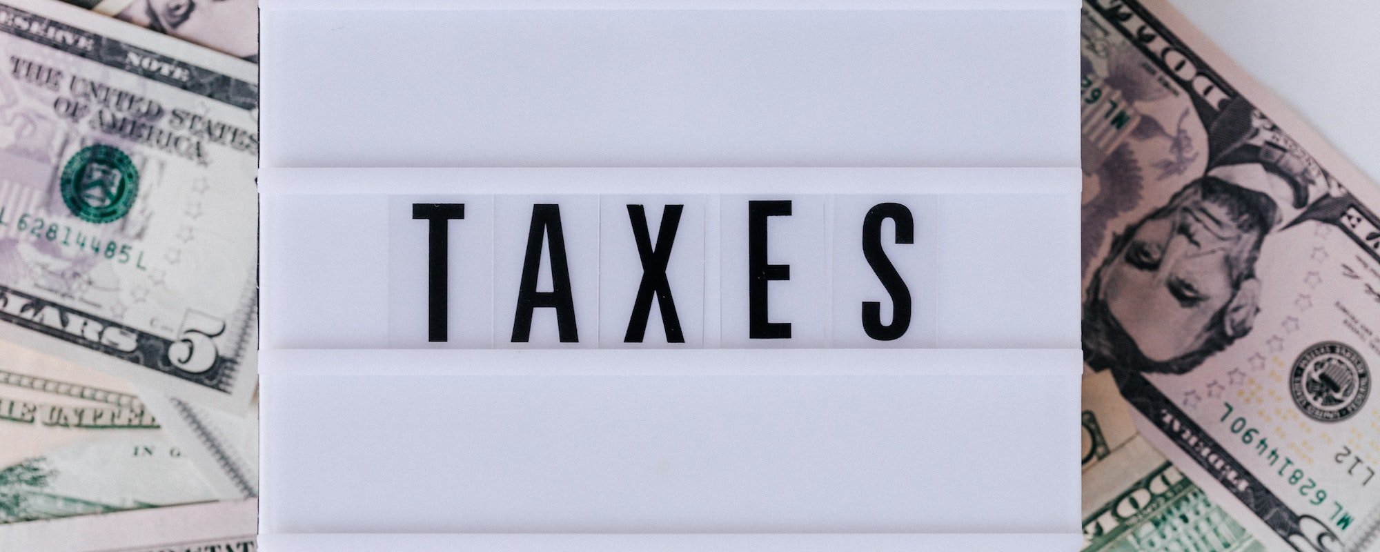 A box sign that says "taxes" lying on money