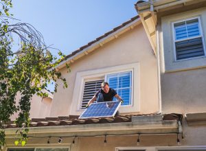 Man Installing Solar Panel On House