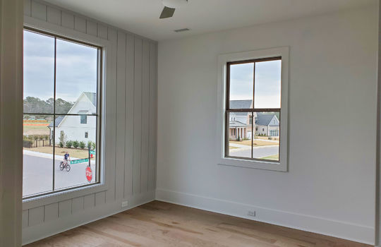 A second-floor guest bedroom painted off-white with an accent wall of vertical paneling.