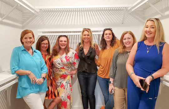 7 of The Cameron Team members standing inside a luxury walk-in closet.
