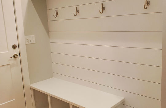 This mudroom dropzone has hooks, a shelf, and a built-in bench with dog bowls and shoe storage.
