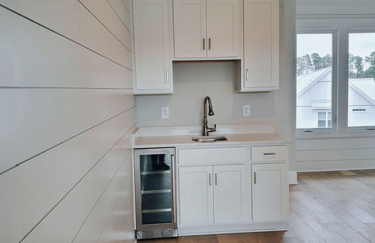 A wet bar with a wine fridge, sink, and cabinets.