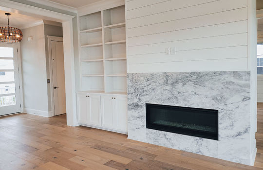 A living room with a gas fireplace, shiplap, and built-in shelves.