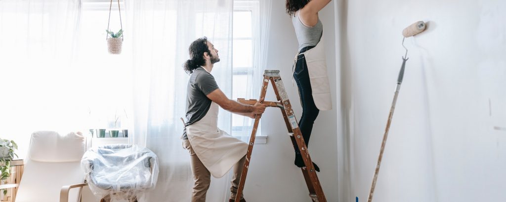 A couple painting the interior of a home.