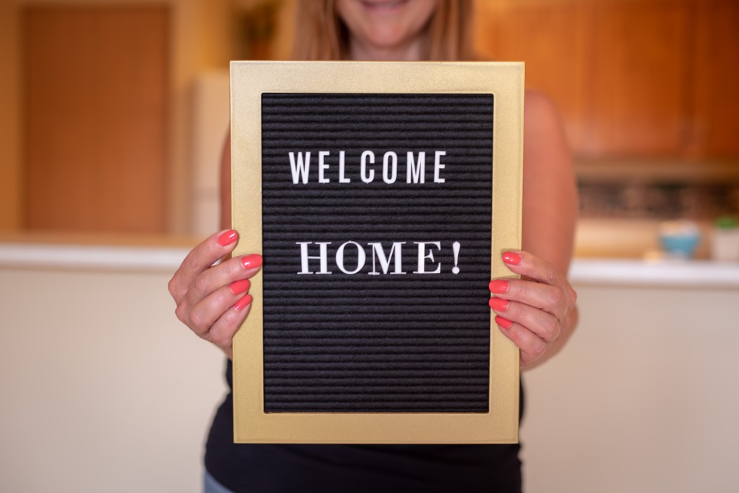 happy-person-holding-welcome-home-sign_t20_8lZ4eQ