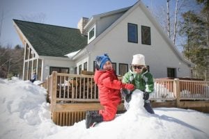 Kids building snowman with mom