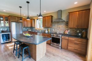 Kitchen with granite counter tops, island, wine fridge, and hood over gas stove