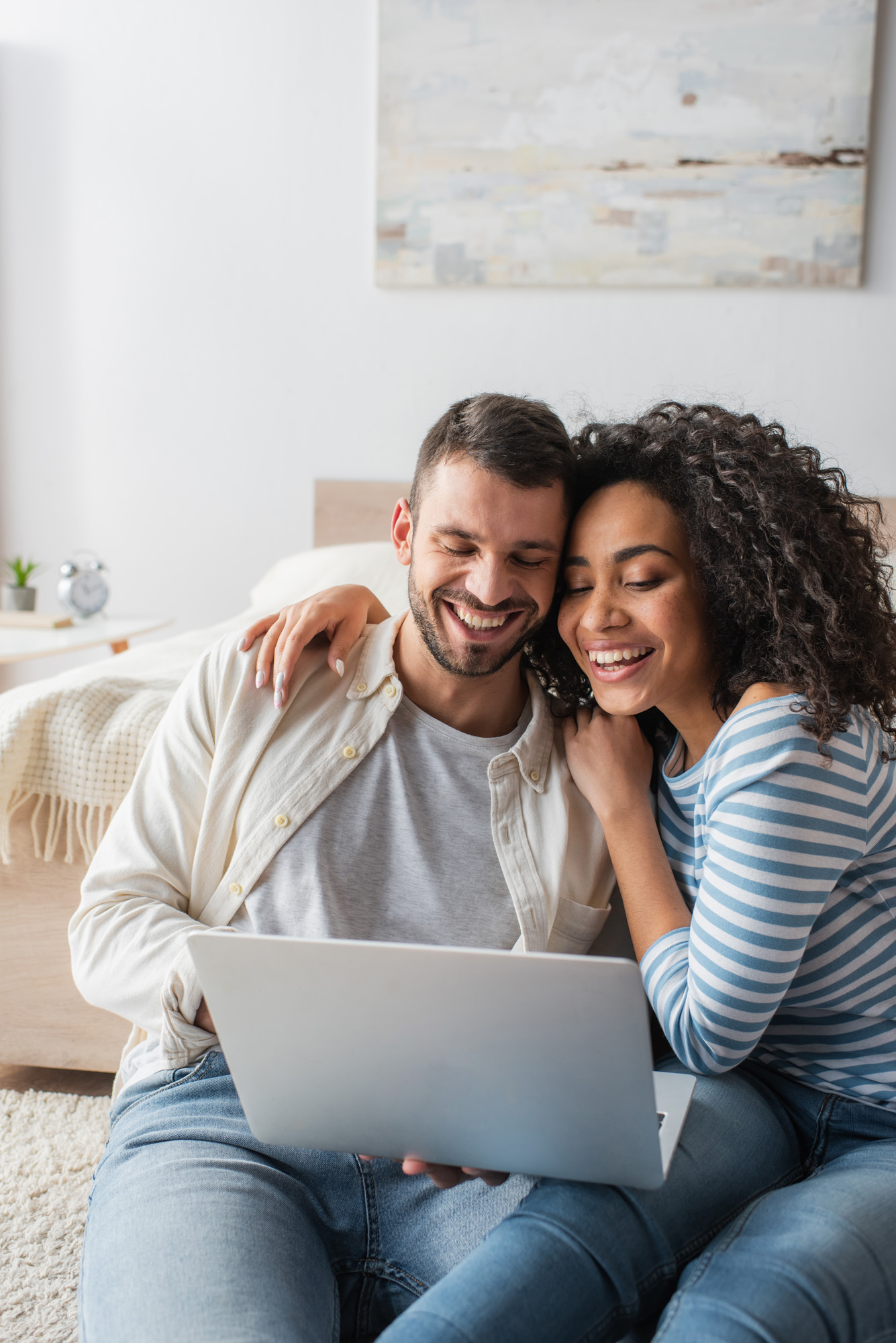 Happy,Interracial,Couple,Smiling,While,Looking,At,Laptop
