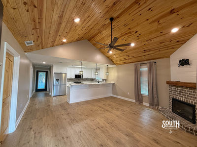 Open living area with vaulted tongue-and-groove pine ceiling, fireplace and adjoining kitchen