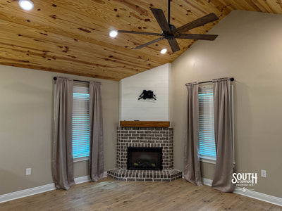 Brick electric fireplace beneath vaulted pine ceiling in the living room