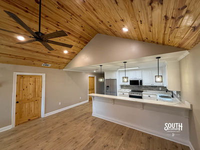 View from living area toward kitchen breakfast bar and pendant lights beneath separate kitchen ceiling