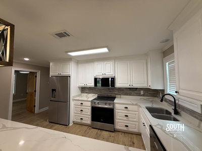 Kitchen with white cabinets, stainless-steel range, refrigerator and sink