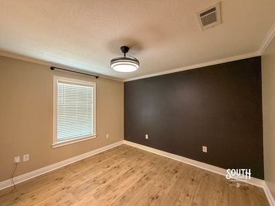 Bedroom with vinyl plank flooring, neutral walls and dark accent wall
