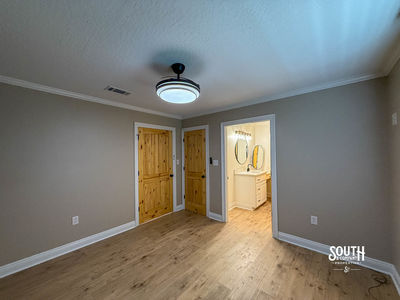 Bedroom with vinyl plank flooring, closet doors and adjacent bathroom entrance