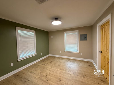 Bedroom with green accent wall, two windows and vinyl plank flooring