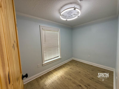 Room with pale blue walls, one window and vinyl plank flooring