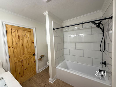 Bathroom tub and shower with white wall tile and black fixtures
