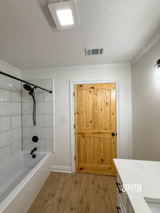 Bathroom tub-shower, white vanity edge and natural pine door