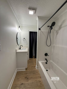 Bathroom with bathtub-shower and stacked washer-dryer in adjoining laundry nook