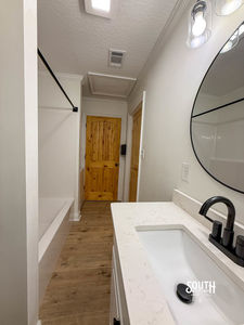 Bathroom with white vanity, black faucet and tub-shower enclosure