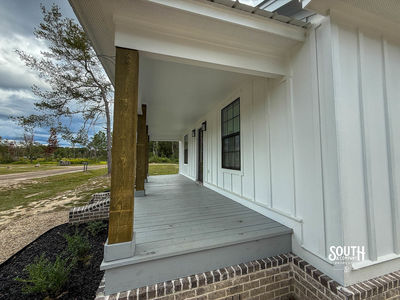 Covered front porch showing board-and-batten siding, timber posts and landscaped bed